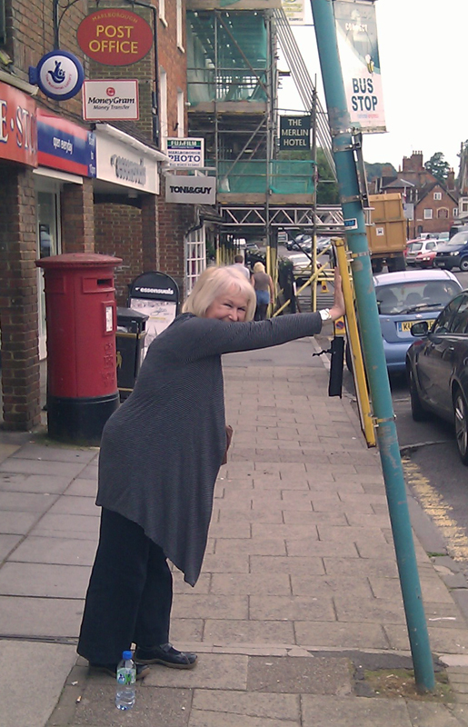 Mayor Edwina Fogg tries to push upright a bent bus stop pole