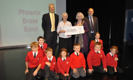 Robert Fraser, the Mayor of Marlborough Edwina Fogg, and Hugh Fraser present a winner's cheque to Marilyn Mason and the children of the Phoenix Brass Band training section