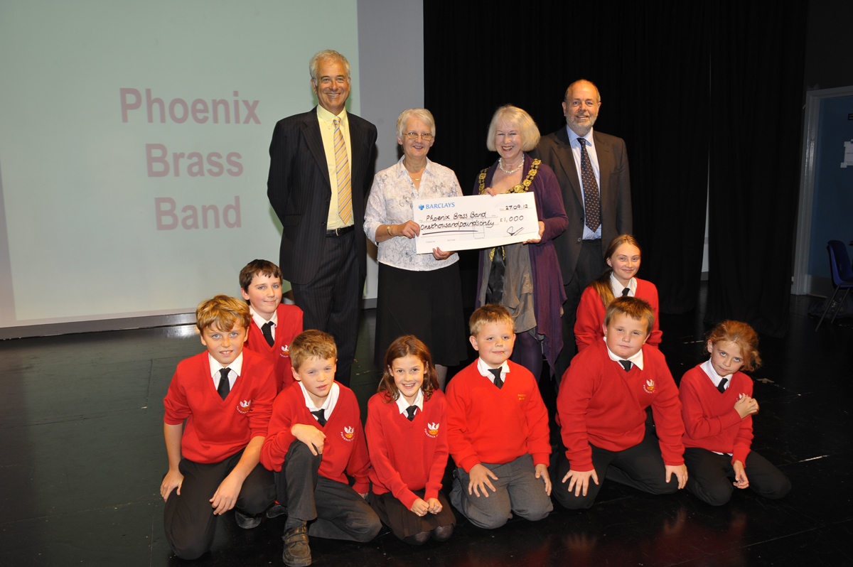 Robert Fraser, the  Mayor of Marlborough Edwina Fogg, and Hugh Fraser present a winner's cheque to Marilyn Mason and the children of the Phoenix Brass Band training section