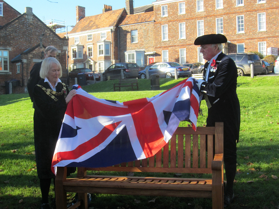Mayor Edwina, helped by ceremonial officer unveils Jim's bench