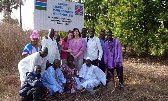 Claire Perry and her daughter Eliza with villagers at the sign marking Marlboroughs link with Gunjur