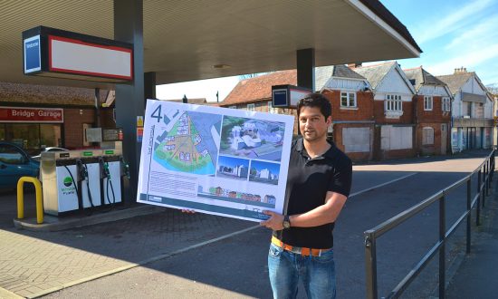 Alex Dean of Bridge Homes with plans for the Bridge Garage site, in front of the filling station forecourt, with the listed buildings in the background