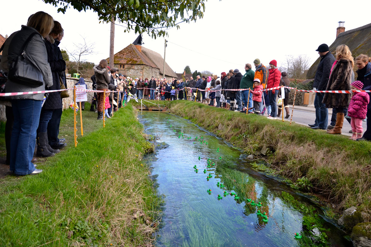 Spectators line the banks of the Winterbourne for the duck race