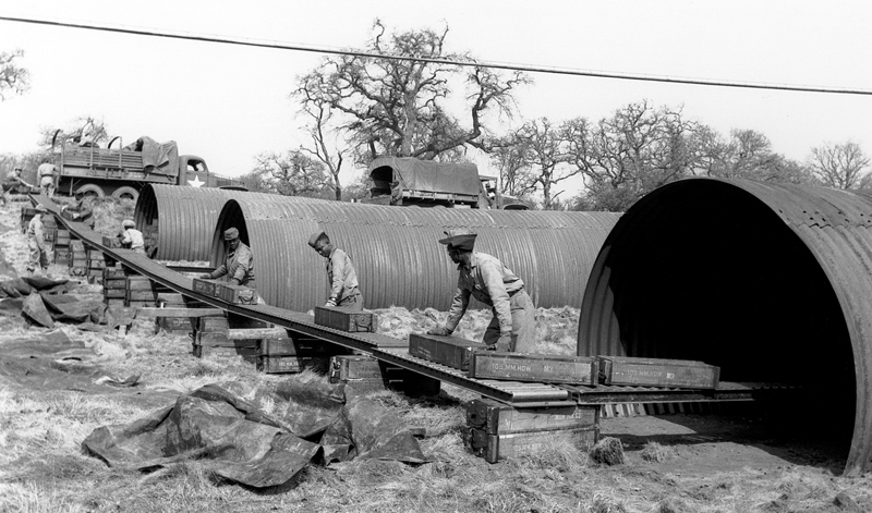 In the forest just south of the A4 near the Stitchcombe turning: American soldiers storing 105 mm ammunition in ‘Elephant Huts’.