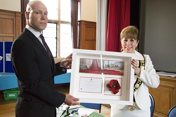 Alek Sagar presents a Tower of London poppy to the mayor