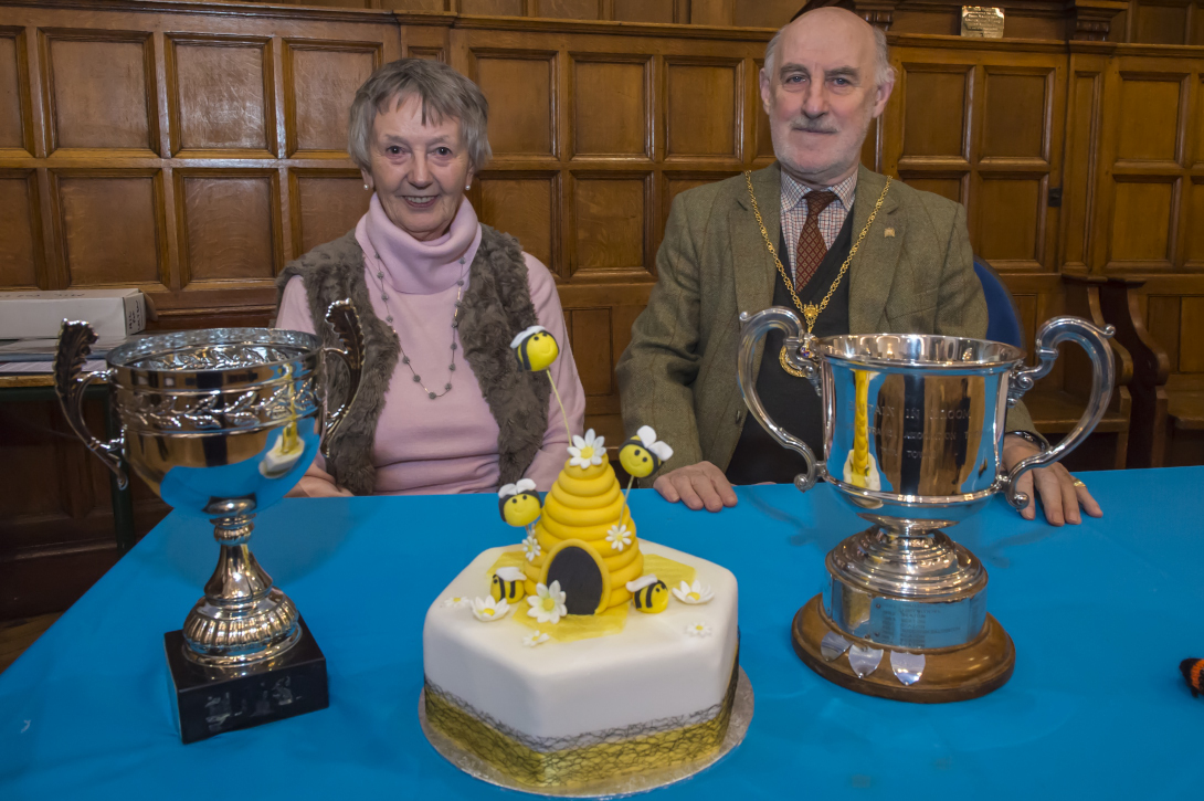 Mayor Cllr Noel Barrett-Morton with Chair Anne Crawley fronted by the South West Tourism Association Cup awarded to the town and the Shaun Creggan Cup won by The Lamb, and a 'Bee themed' cake which would be a worthy winner of any 'Great Marlborough Bake-Off'