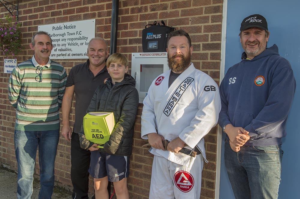 Kevin Palmer of the Gracie Brazilian Jiu Jitsu Martial Arts and Self Defence School declares the new Difbrillator open for use, supported by (l-r) Marlborough Town Chair Wally Ash, MYFC coach Keith Marshall, MYFC U14 Colts player Will Slater and MYFC Chair Stuart Slater