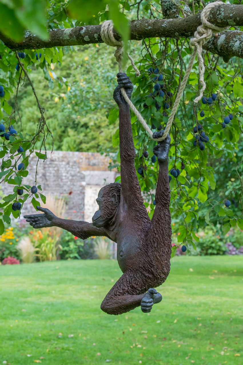 'Ginger' the monkey reaches out to grab a plum as she hangs from a tree in Avebury Manor's Orchard. By Stroud sculptor Martin Adamson