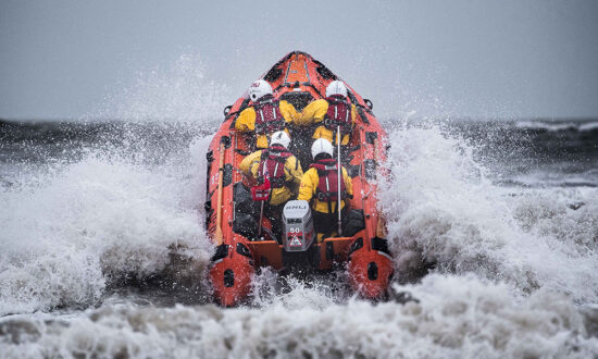 An inshore lifeboat - Inflatable D Class - powering out through the surf